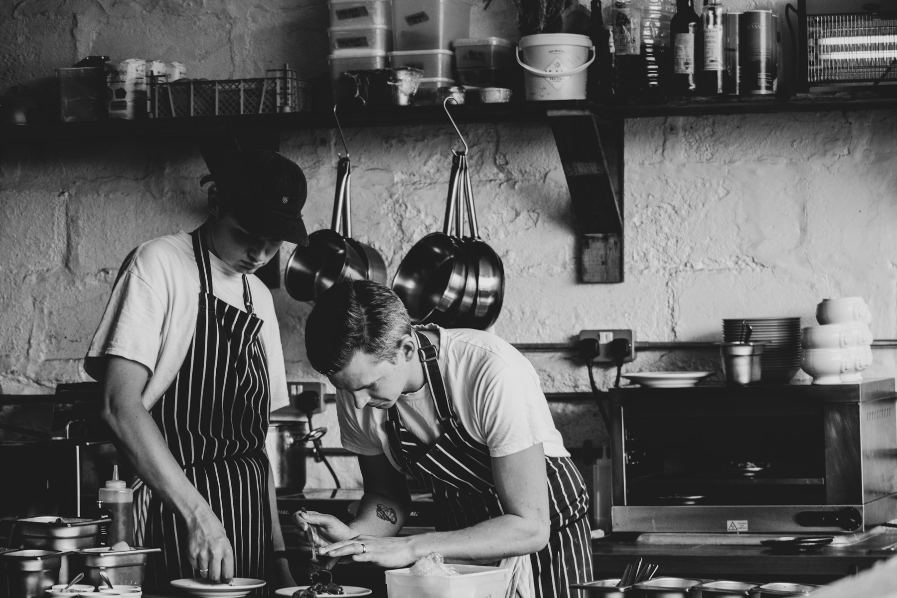 Dos cocineros emplatan en la cocina de un restaurante pequeño